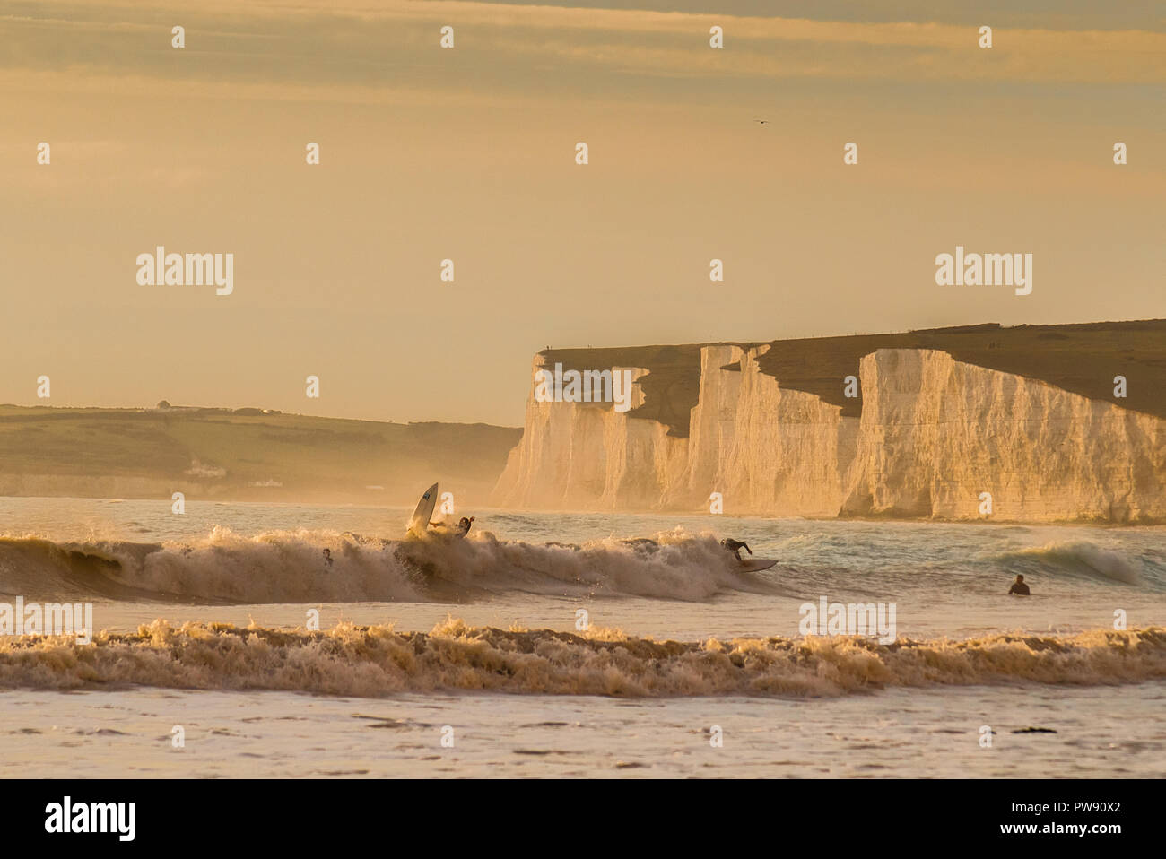 Birling Gap, Eastbourne, East Sussex, UK..13. Oktober 2018..EIN glorreicher Balmy Abend mit warmem Wind aus dem Süden. Surfer gegen den prächtigen Rückenabfall der Kreidefelsen Von Seven Sisters. ... Stockfoto