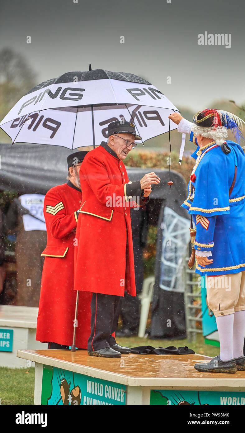 Southwick, UK. 14. Oktober 2018. Der amtierende Weltmeister der Männer, John Riley, eine achtzigjährige Chelsea Rentner, richtet sich auf die conker seines Gegners, Roy Palmer (stadtausrufer für Mablethorpe), bei der Eröffnung der 2018 Welt conker Meisterschaften an einem regnerischen Tag in Southwick, UK; John Riley gewann den Kampf. Quelle: Michael Foley/Alamy leben Nachrichten Stockfoto