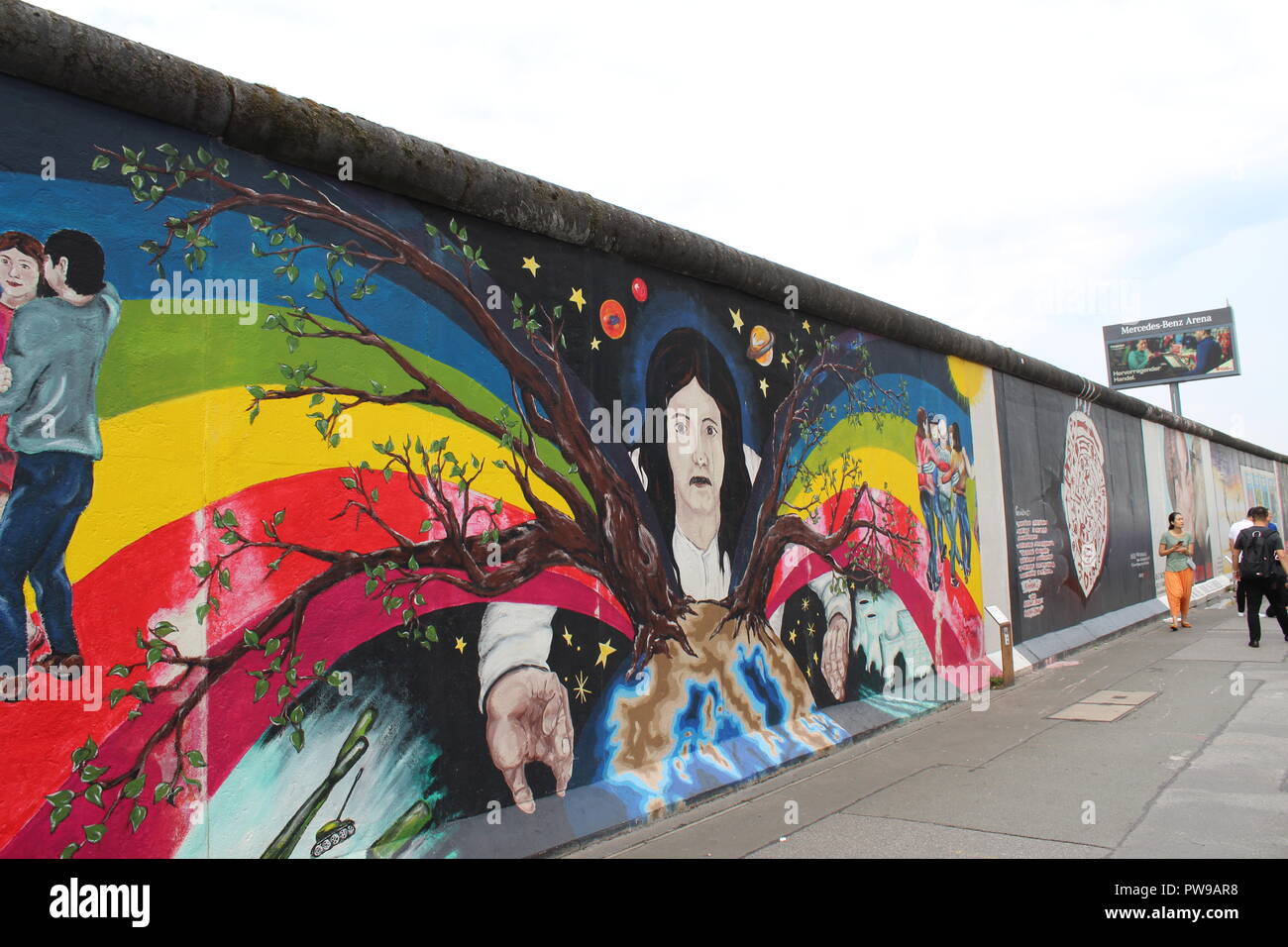 East Side Gallery - Berliner Mauer - Europas Frühjahr Malerei von Catrin Resch mit Touristen im Hintergrund an einer anderen Malerei suchen - Natur Stockfoto