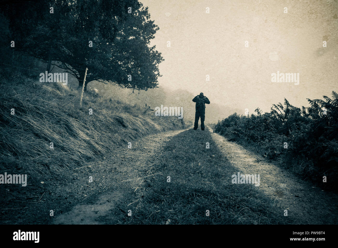 Eine einsame Silhouette einer Abbildung auf einem nebligen Pfad in der Landschaft mit einem Oldtimer, grunge Duo Tone bearbeiten Stockfoto