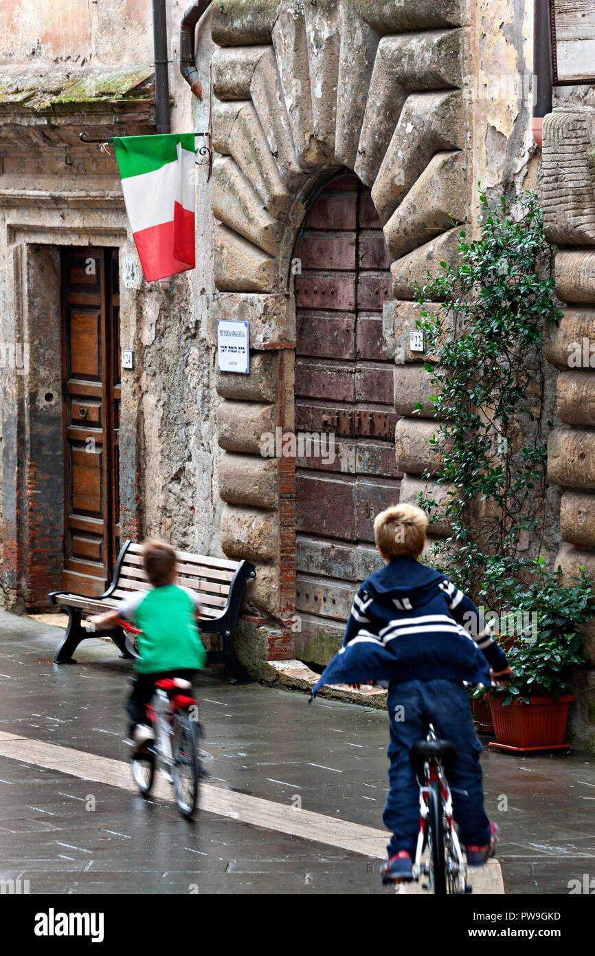 2 Jungen auf dem Fahrrad in einer Straße, Sorano, Provinz Grosseto, Toskana, Italien Stockfoto