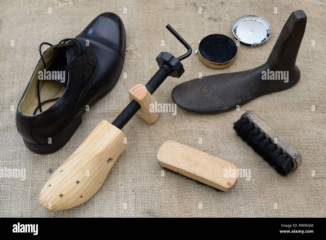 Verschiedene Objekte für die Wartung und Reparatur von Schuhen, einschließlich, Schuhspanner, letzte, Polieren und Bürsten neben einem Mans schwarz Schuh. Stockfoto