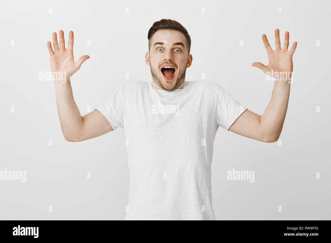 Studio shot von Angeregten gesund aussehenden Mann mit Borsten, Palmen Höhe und Geschrei von Freude und Staunen mit tollen Nachrichten zu faszinierenden Geschichte reagieren überrascht zu werden Stockfoto