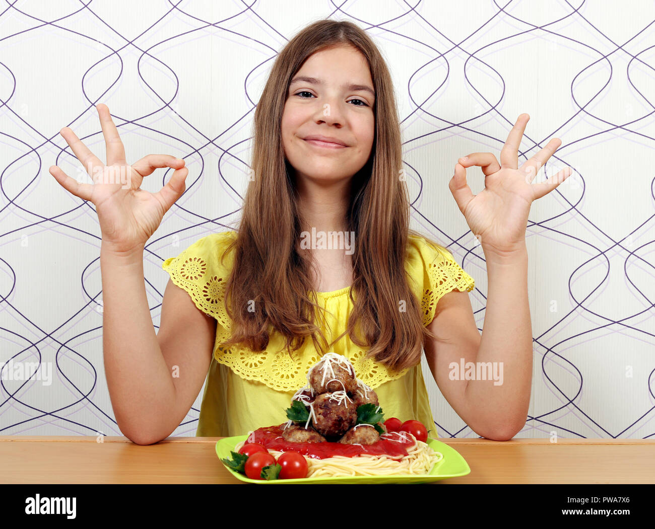 Glückliches Mädchen mit Spaghetti und Frikadellen und ok Handzeichen Stockfoto