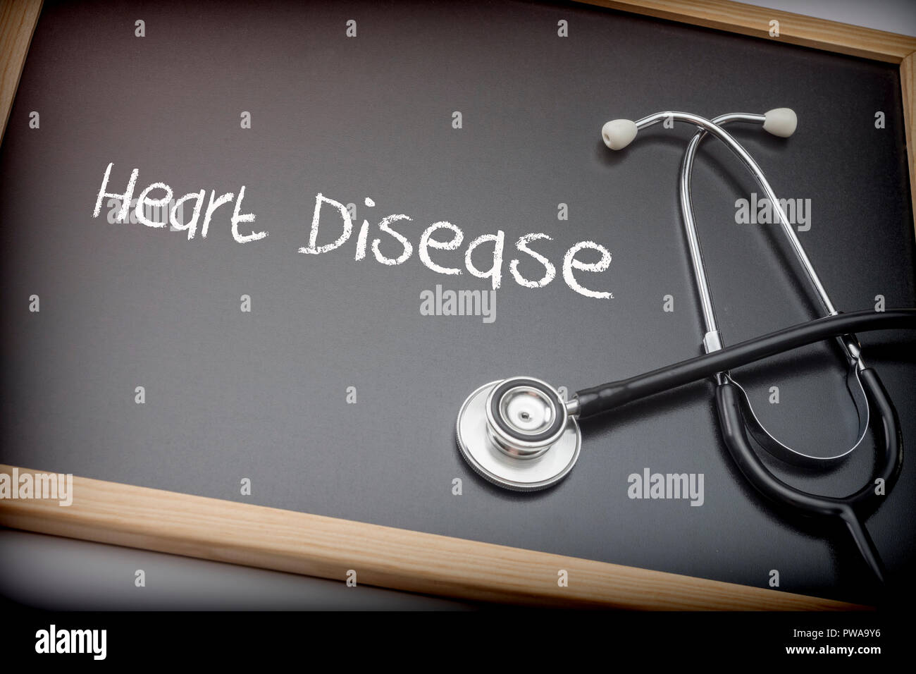 Wort Herzkrankheit mit Kreide auf einer Tafel schwarz Neben einem Stethoskop, konzeptionelle Image geschrieben Stockfoto