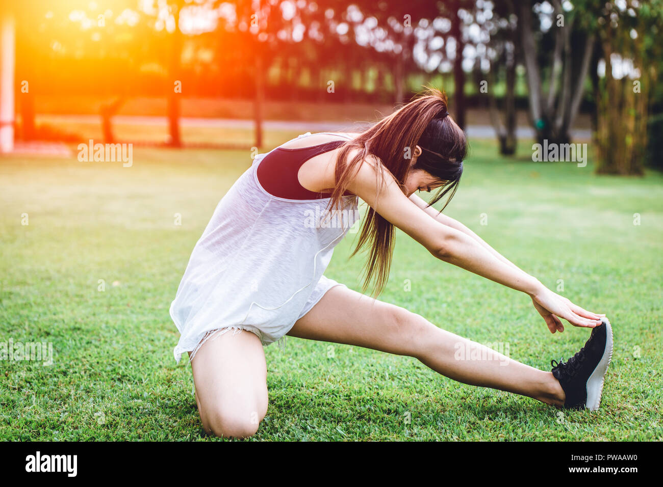 Gesunde schlanke Mädchen leg stretching Aufwärmen vor Laufen oder Joggen Stockfoto
