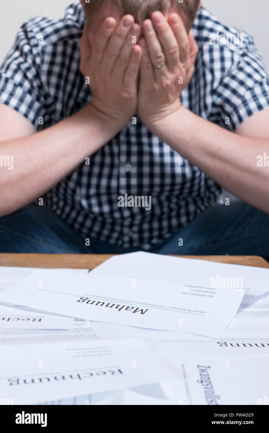 Ein Mann mit Geld Probleme mit Rechnungen stapeln Sie die Tabelle hat Kopfschmerzen. Stockfoto