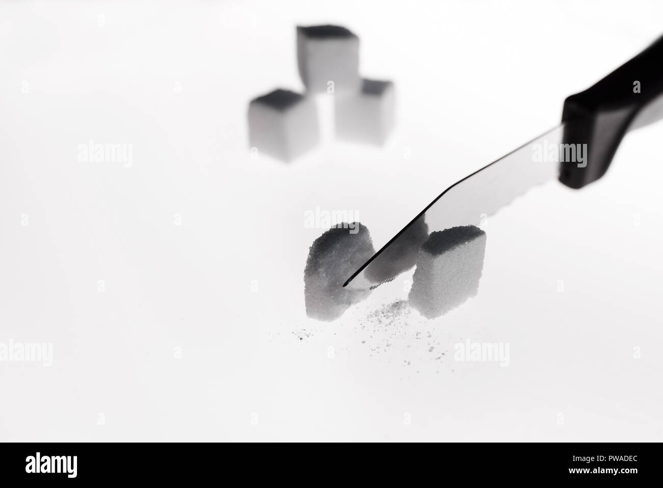 Sehen wir die Spitze des Messers, dass Kürzungen in einem halben Würfel Zucker. Stockfoto