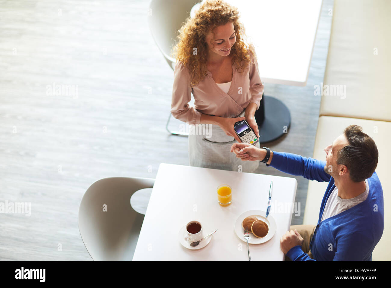 Smart Geschäftsmann, Sitzen, Tisch serviert und Zahlen für seine Mahlzeit von smartwatch Stockfoto