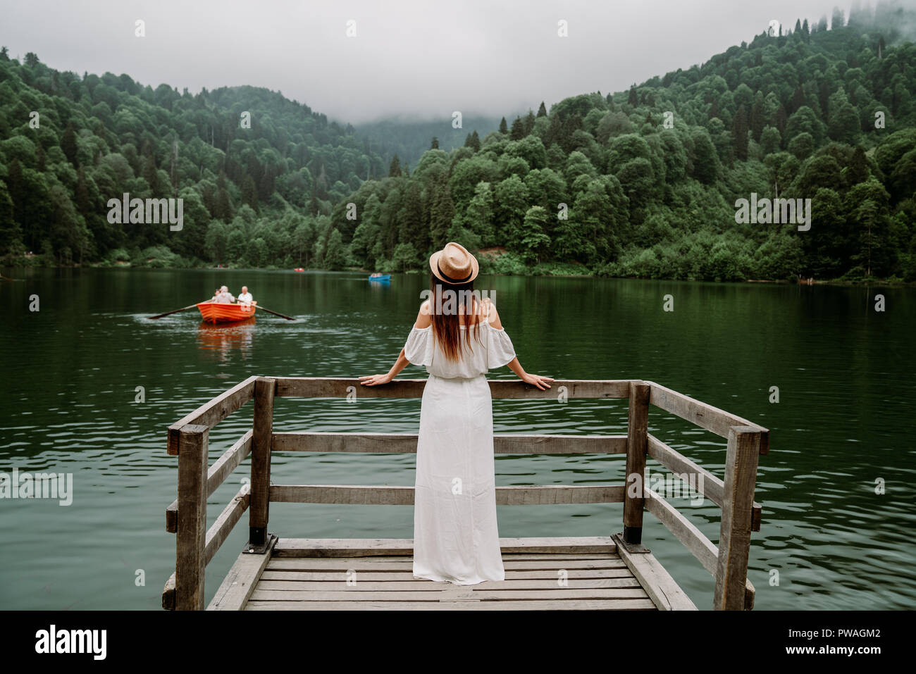 Die Frau mit Hut und weißen Kleid stehend gegen See in der Natur Stockfoto
