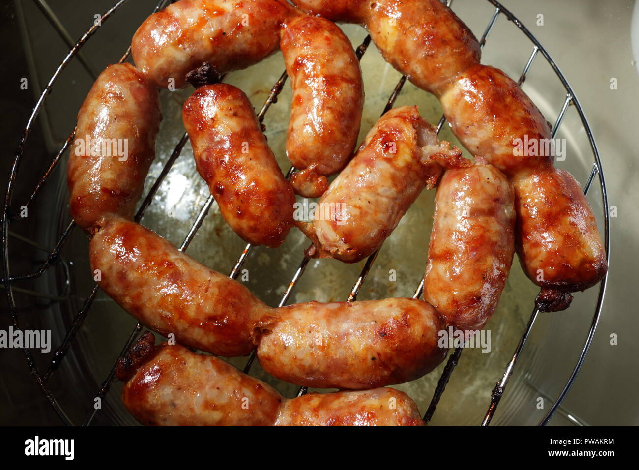 Goldbraune Isanwürste, perfekt gebacken, stehen verführerisch auf einem Backblech. Diese Würstchen sind ein Grundnahrungsmittel der thailändischen Küche. Stockfoto