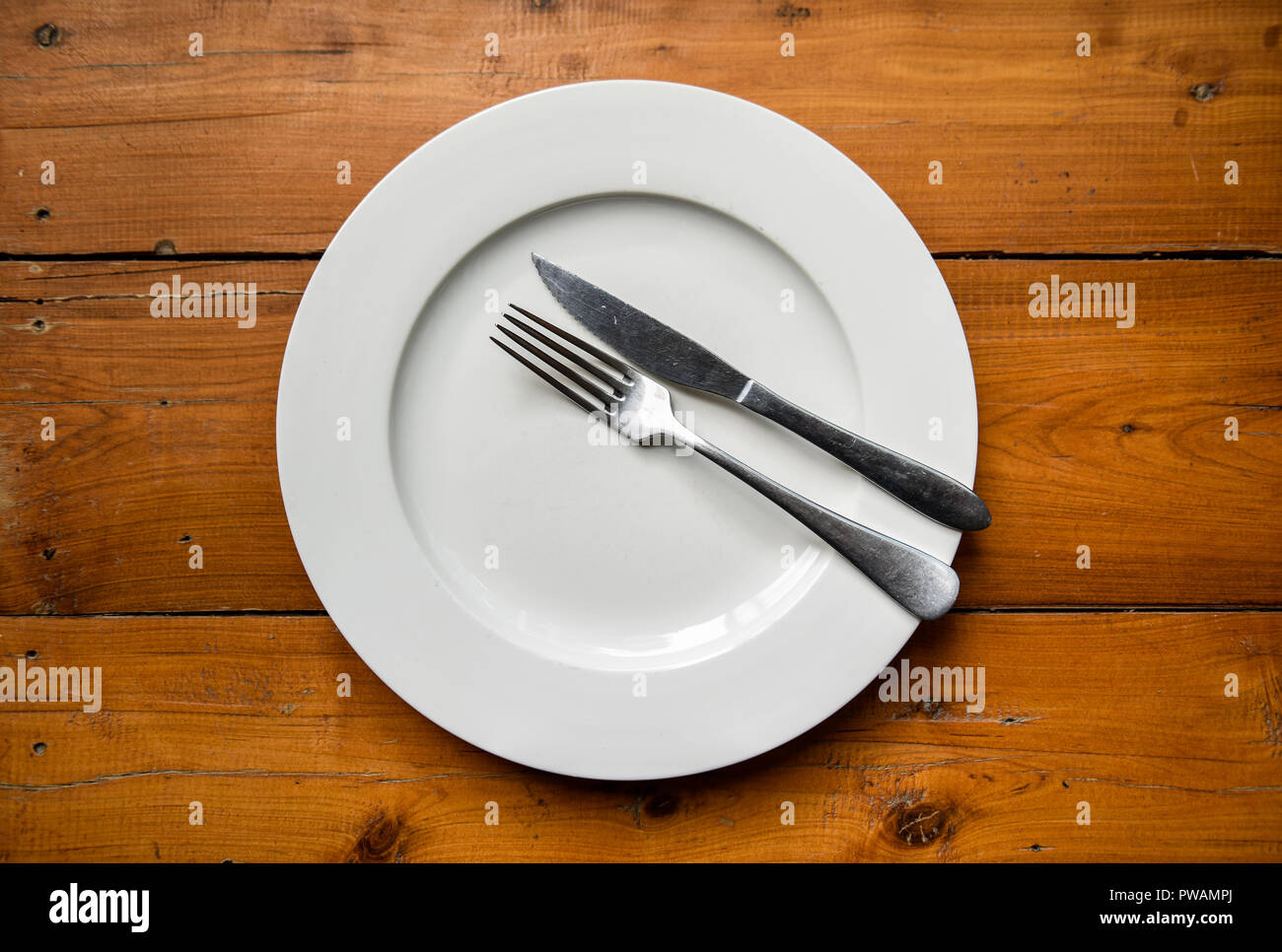 Ansicht von oben in Silber Messer und Gabel auf runde weiße Platte auf holztisch Innovationsvermarktung tätig, dass das Abendessen fertig ist Stockfoto