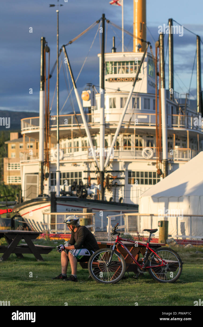 Whitehorse, Kanada. SS. Klondike Dampfschiff mit Radfahrer sitzen auf einer Bank vor in einem Sommertag. Stockfoto