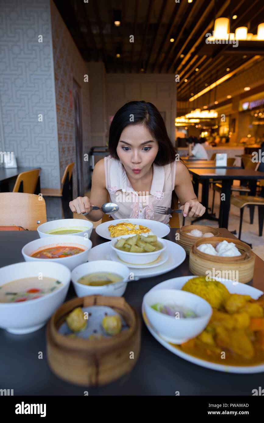 Junge schöne asiatische Frau essen im Restaurant mit einer großen Auswahl an Speisen Stockfoto