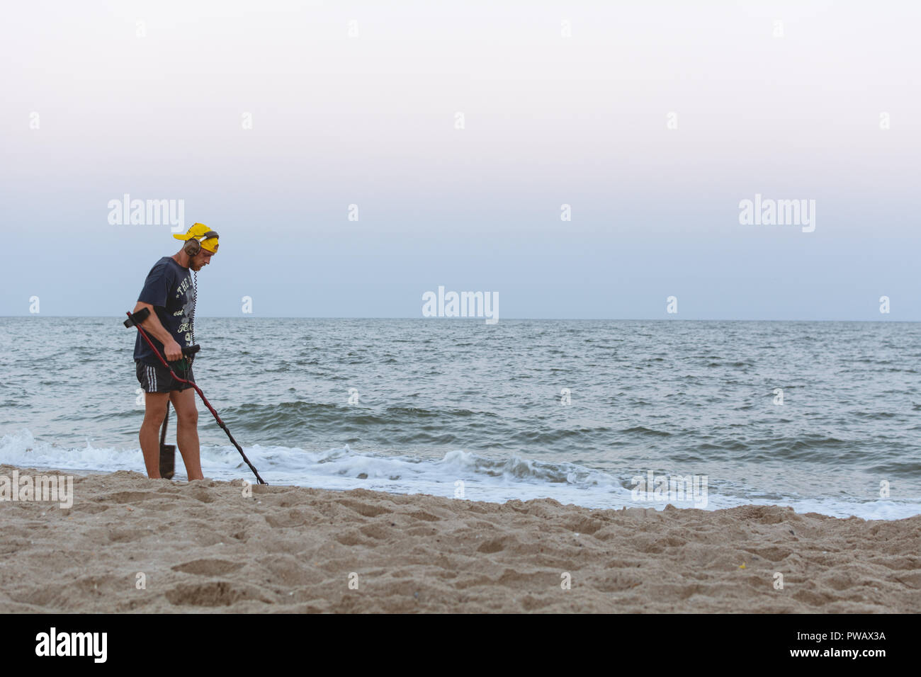 Treasure Hunter mit einem Metalldetektor Spaziergänge am Strand des Schwarzen Meeres nach Sonnenuntergang auf der Suche nach Schatz Stockfoto