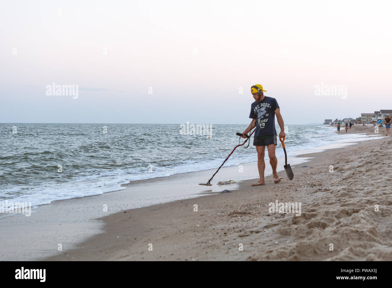 Treasure Hunter mit einem Metalldetektor Spaziergänge am Strand des Schwarzen Meeres nach Sonnenuntergang auf der Suche nach Schatz Stockfoto
