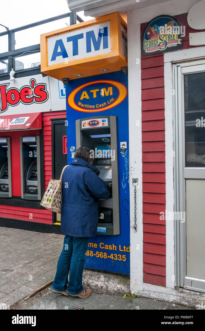 Eine Frau Geld Rückzug aus einem Maritimen Cash Ltd ATM Geldautomaten in St. John's, Neufundland, Kanada. Stockfoto