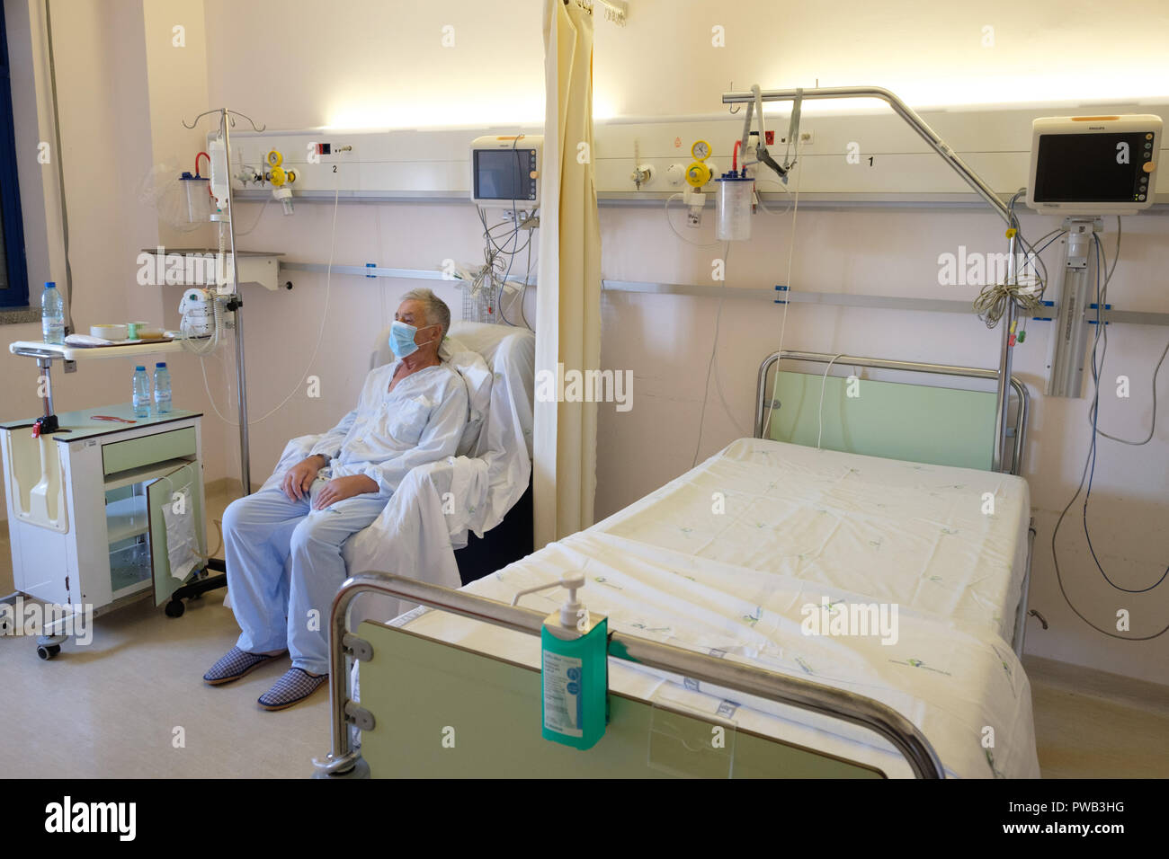 Patienten mit Maske, während in einem Krankenhaus Schlafzimmer sitzen Stockfoto