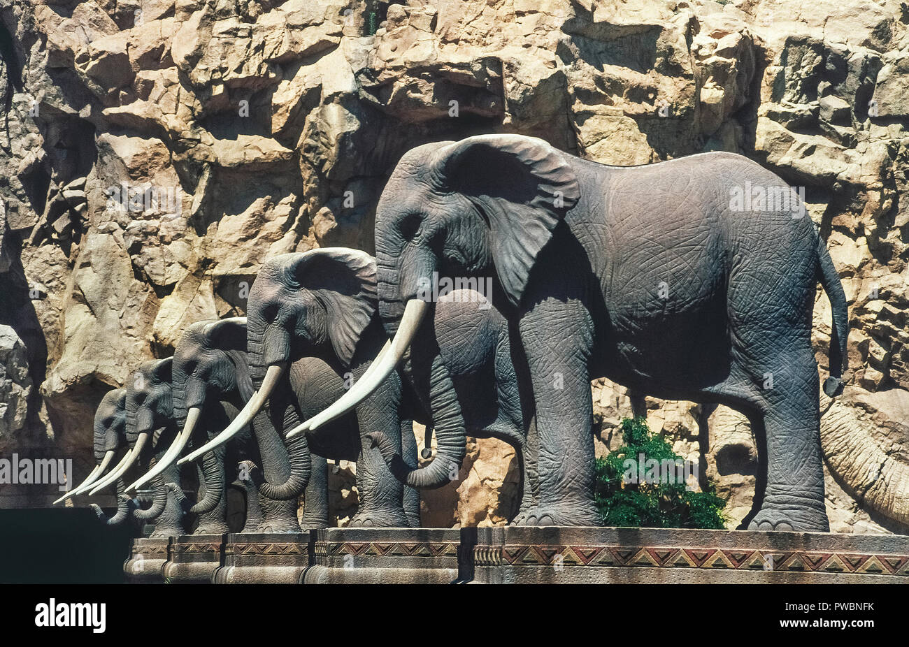 Skulpturen von afrikanischen Elefanten Futter die Brücke von Zeit zu den outdoor Attraktionen in Sun City, einem weltbekannten Ferienort in der North West Provinz von Südafrika. Die berühmte Spielplatz bietet Urlaubern alles, was von einem Wasserpark mit Wellenbad, Golfplätze, ein Spielcasino, Heißluftballon-Fahrten, und sogar Tier Safaris in den angrenzenden Wildpark. Stockfoto