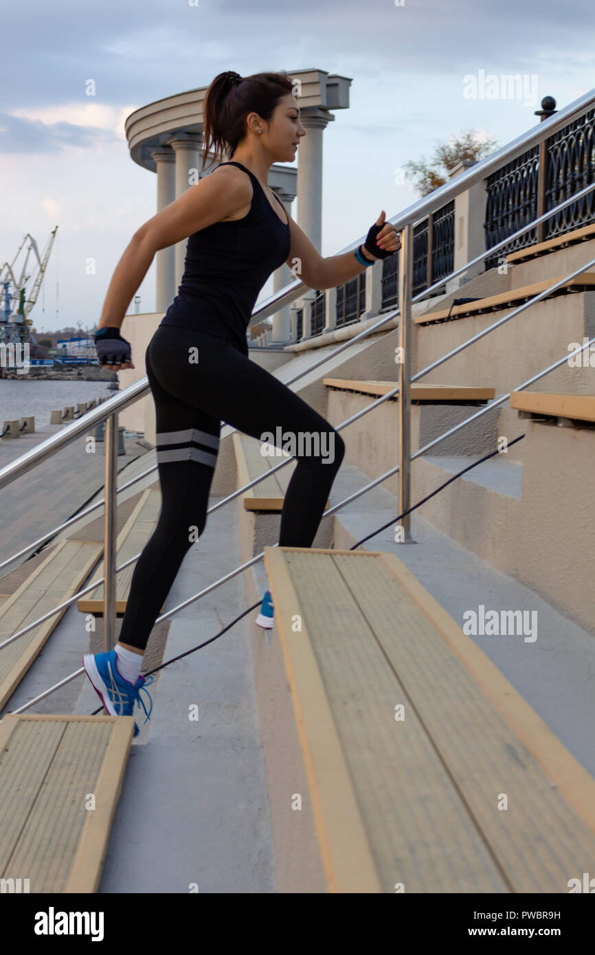 Junge und attraktive Mädchen, die bei Sonnenuntergang in den Stadtpark. Gesunde fitness Frau läuft im Freien. Amur in Chabarowsk Horizont im Hintergrund. Stockfoto