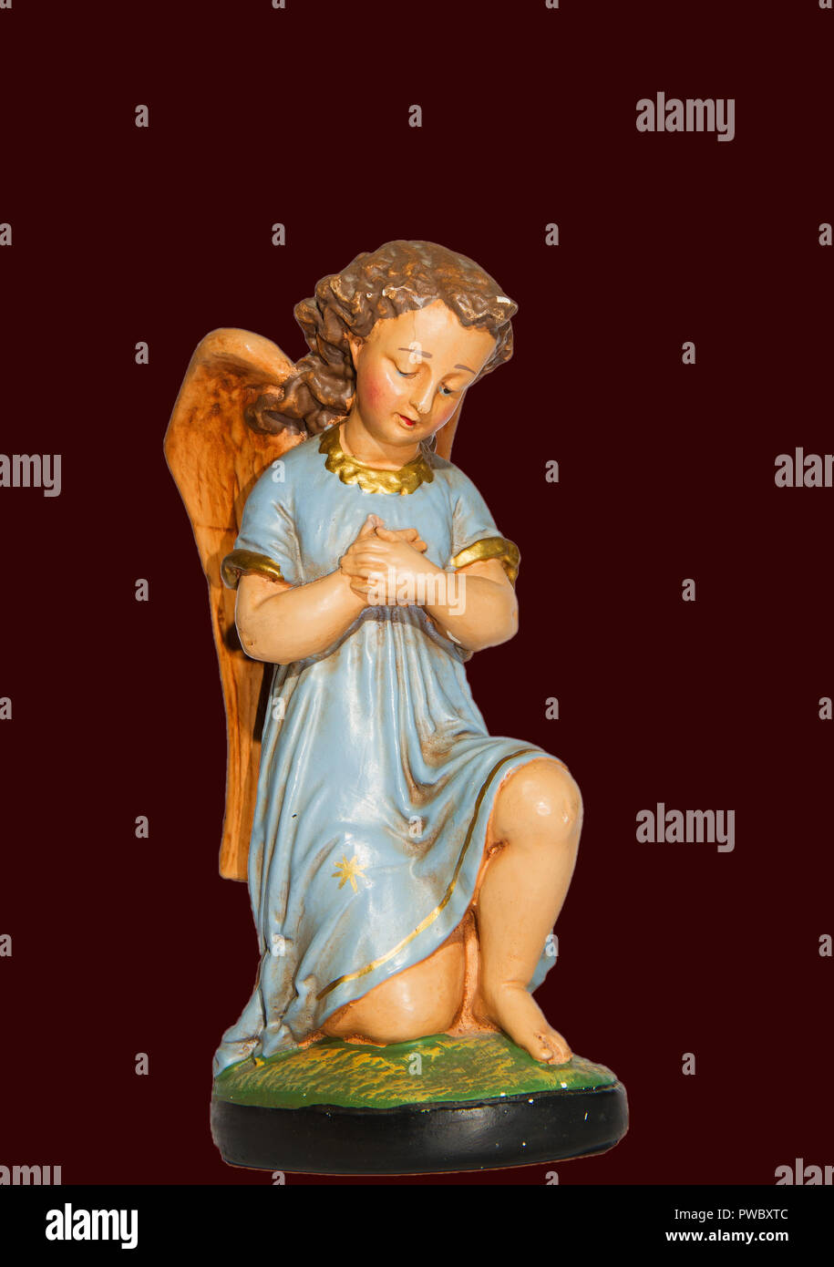 Engel im Gebet mit blauem Kleid, Gips, Statue aus Gips und Handbemalt, auf dunkelrotem Hintergrund isoliert Stockfoto
