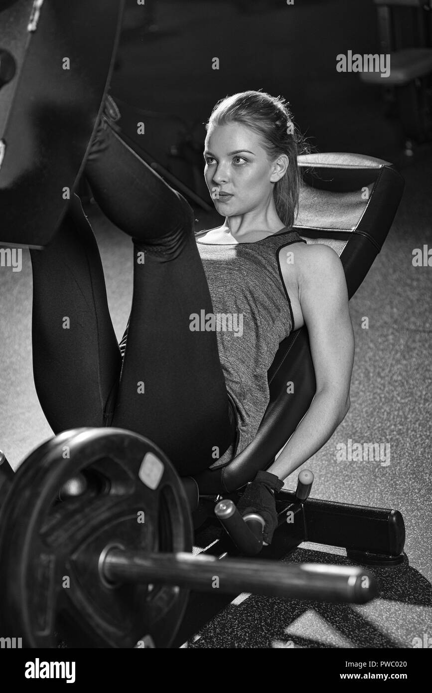 Sportliche Frau mit Gewichten-Presse-Maschine für die Beine. Fitness-Studio. Stockfoto