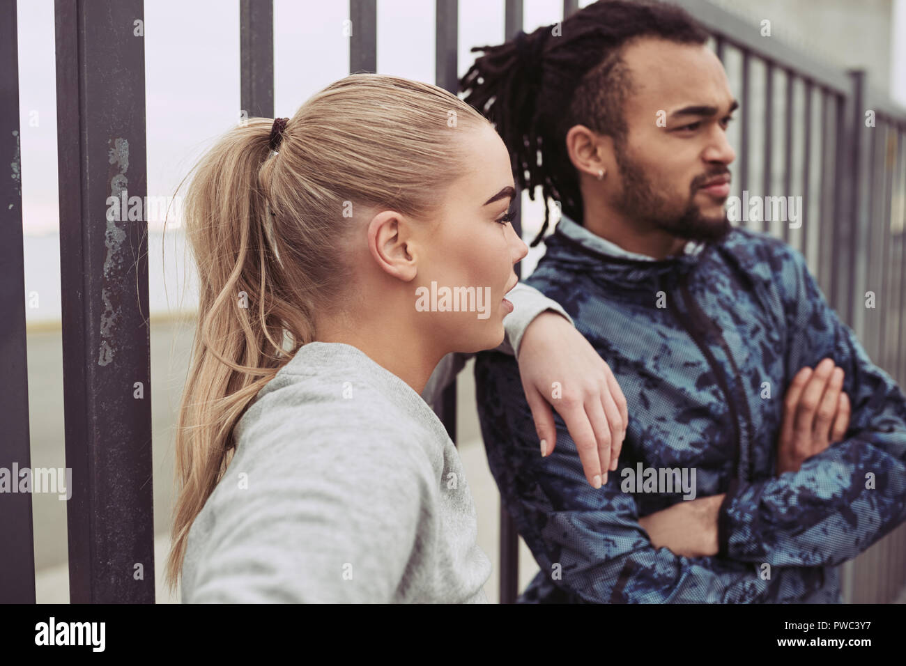 Diverse junges Paar in Sportkleidung suchen Beim zusammen Stehend außerhalb Lesung für einen Lauf zu gehen konzentriert Stockfoto