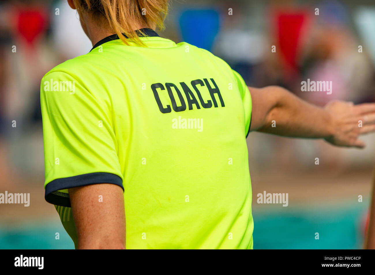 Rückansicht des weiblichen Trainer Schwimmen TRAINER T-Shirt tragen, die Anweisung zu ihrer Schwimmer Stockfoto