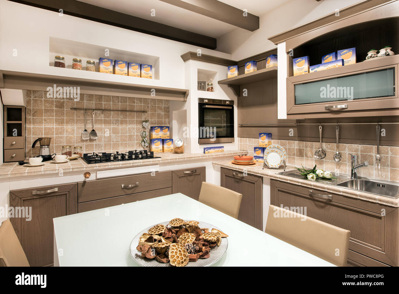 Rustikal oder Küche mit Kochutensilien, in Schaltschränken mit Fliesen- Splash Back gebaut, Geräten und einem zentralen Tisch mit hausgemachten Cookies Stockfoto