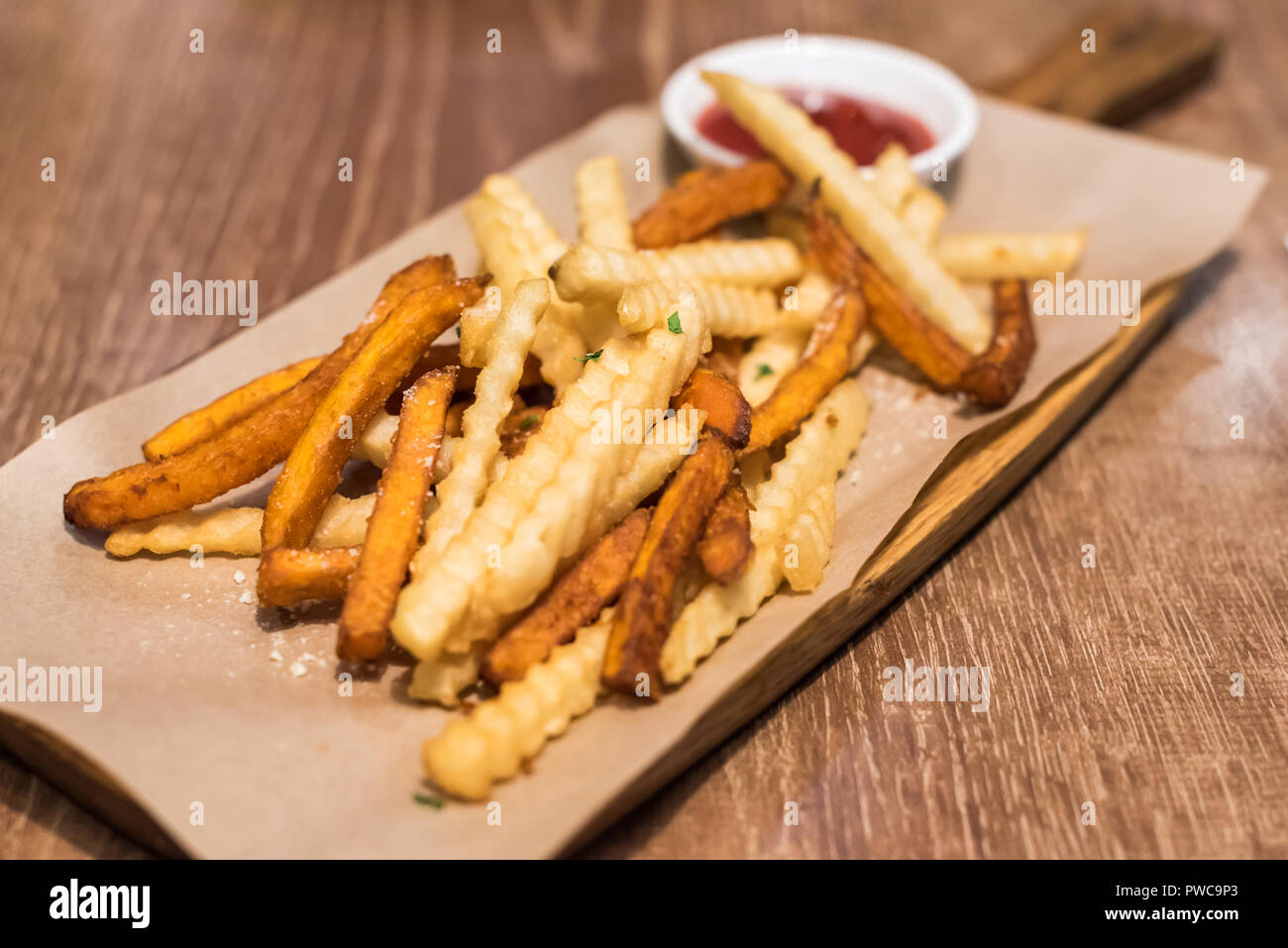 Bündel von Pommes Frites mit Ketchup Soße auf einer hölzernen Tisch Stockfoto