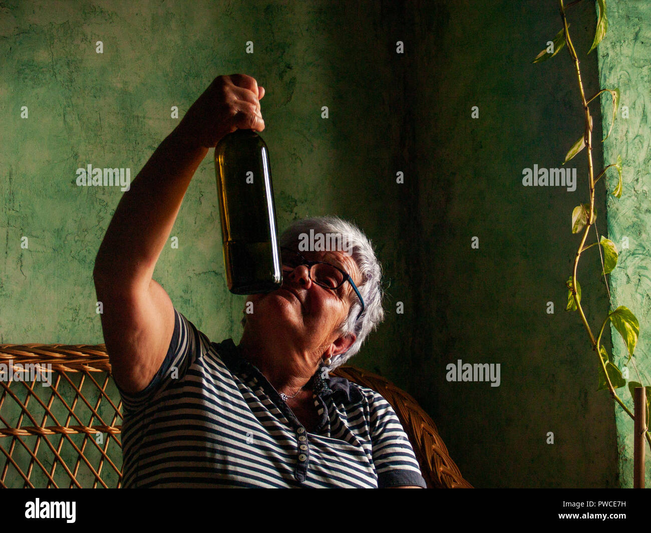 Eine betrunkene Frau trinkt aus einer Flasche Wein in der Hand. Stockfoto