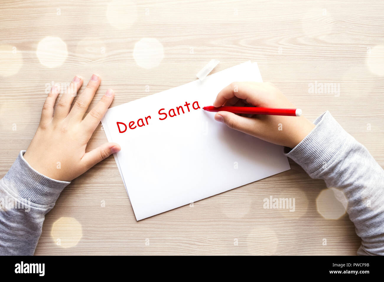Die Hände des Kindes schreiben Brief an Santa auf dem Tisch. Stockfoto