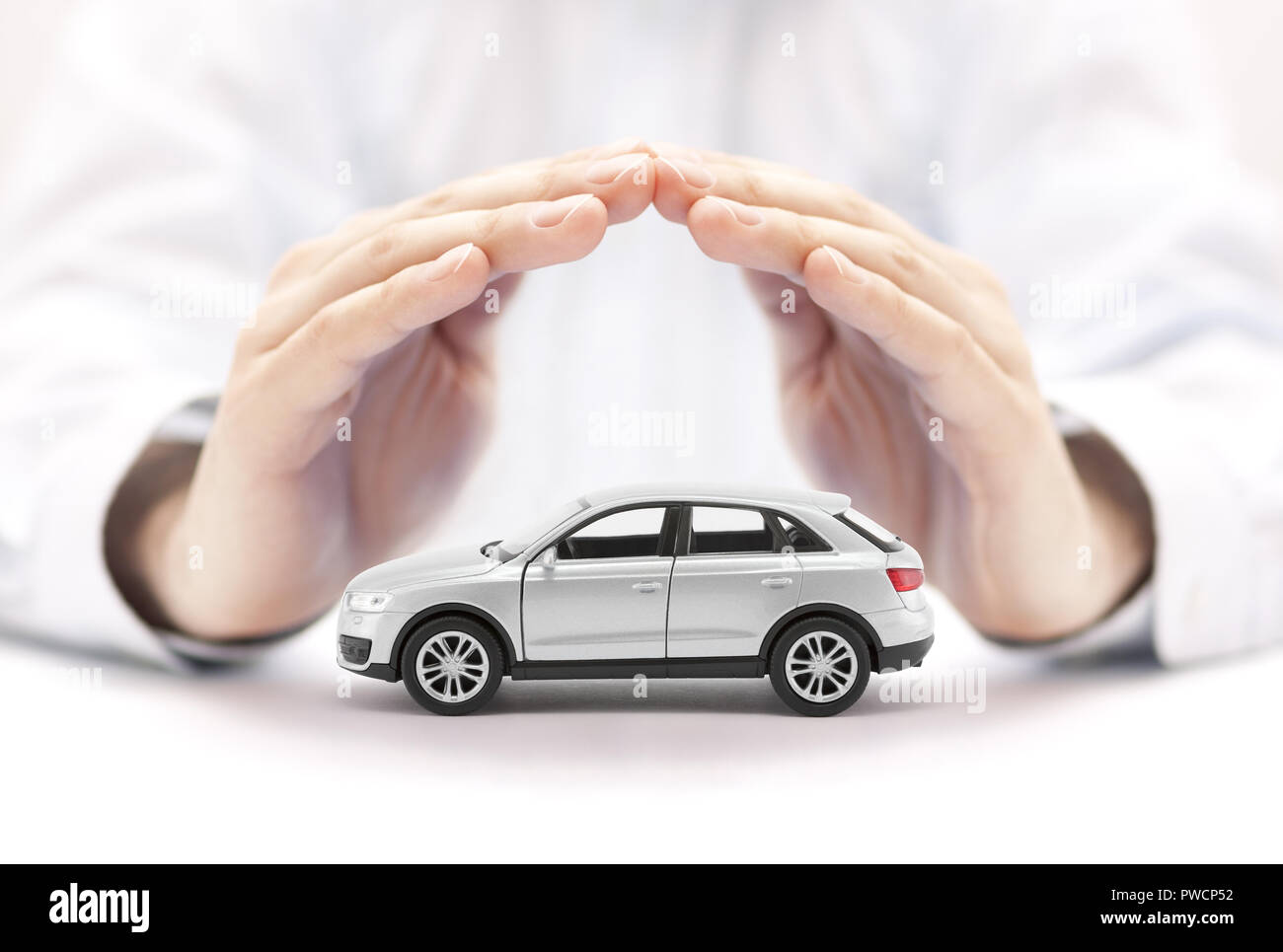 Auto Versicherung. Kleine silberne Auto mit Händen bedeckt. Stockfoto