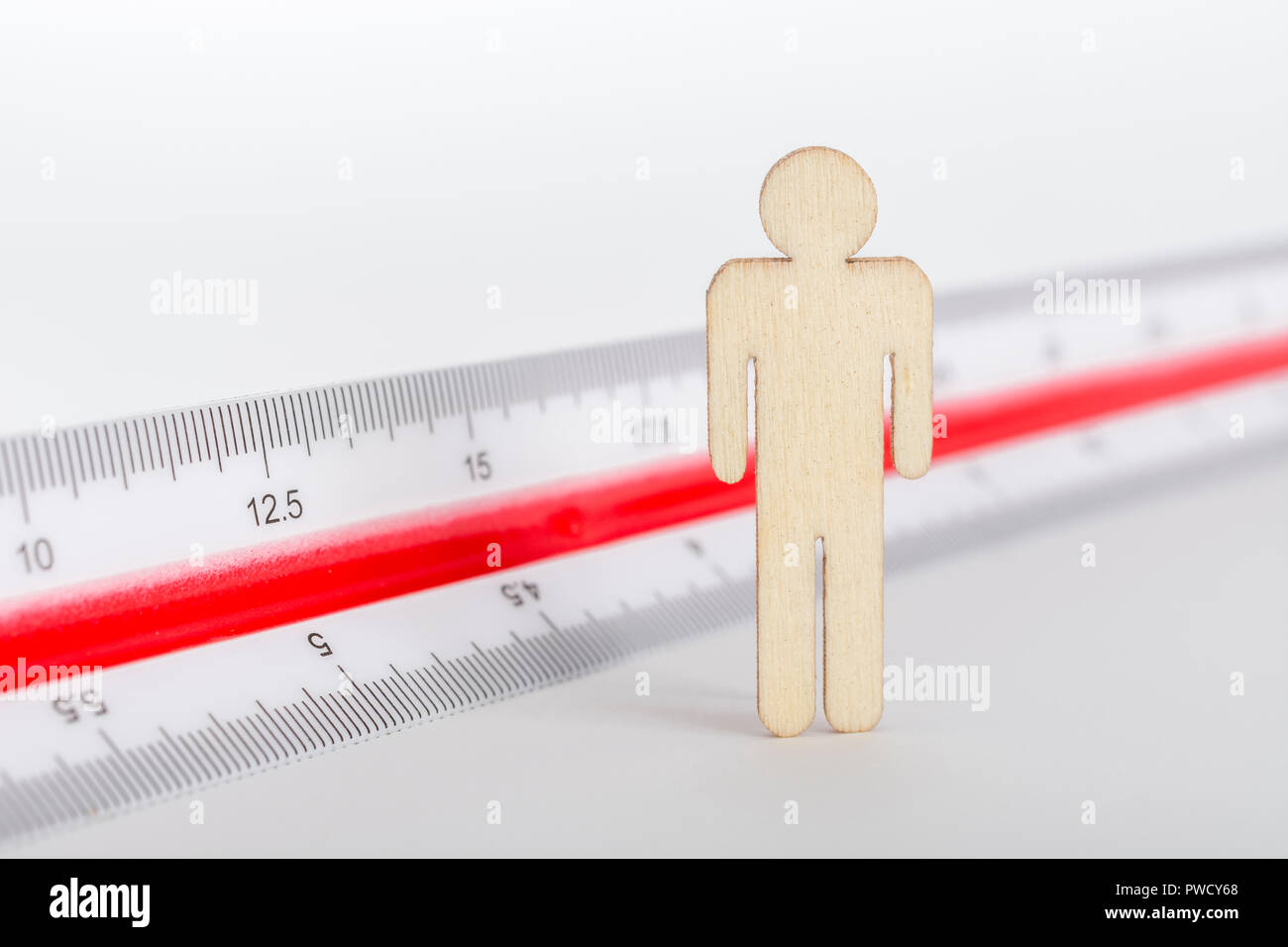 Makro kleine Laser-cut Holzfigur und Lineal. Metapher Messen persönliche Leistung, Demographie Konzept, Produktivität, die Maßnahme von einem Mann bekommen. Stockfoto