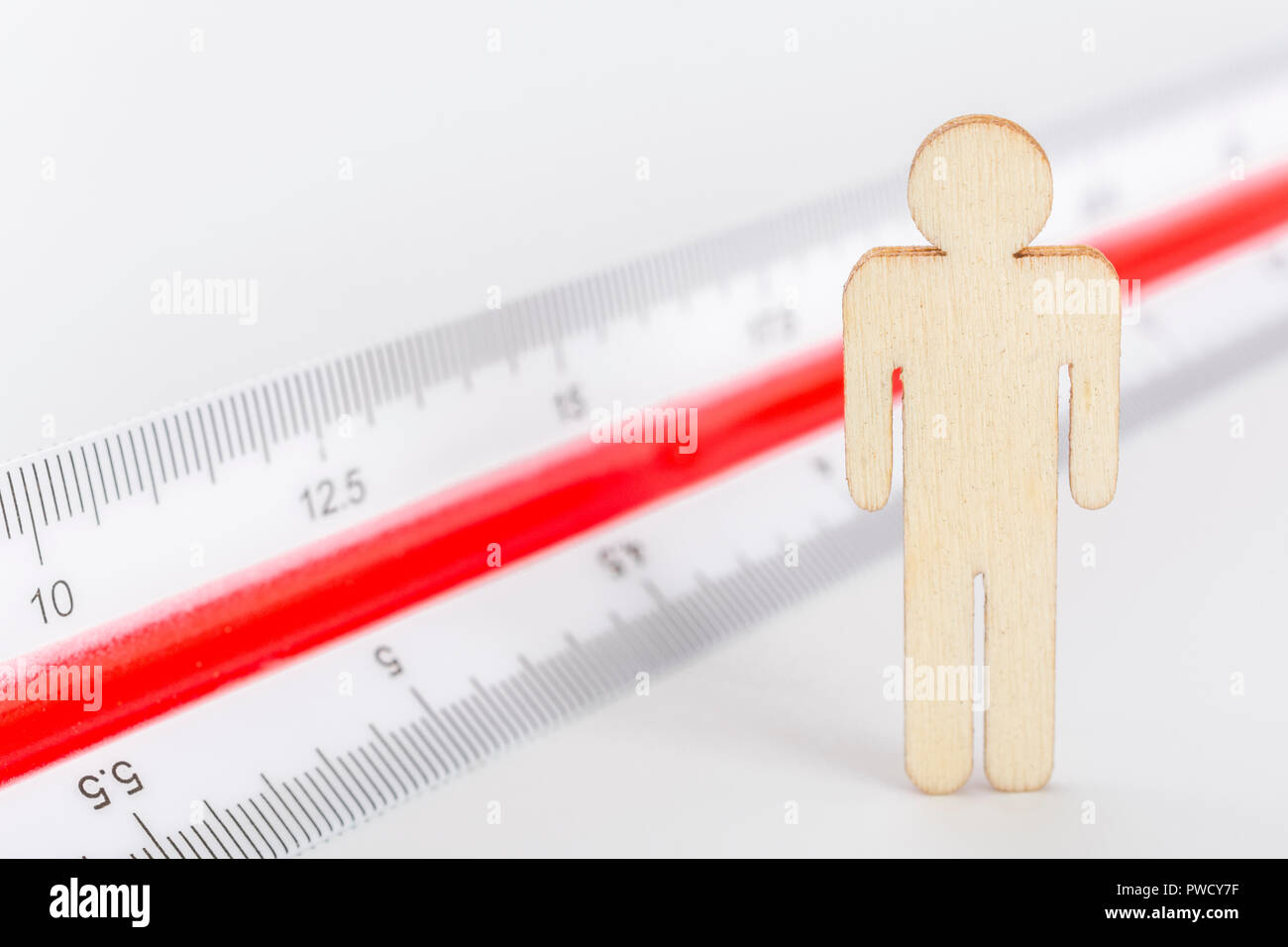 Makro kleine Laser-cut Holzfigur und Lineal. Metapher Messen persönliche Leistung, Demographie Konzept, Produktivität, die Maßnahme von einem Mann bekommen. Stockfoto