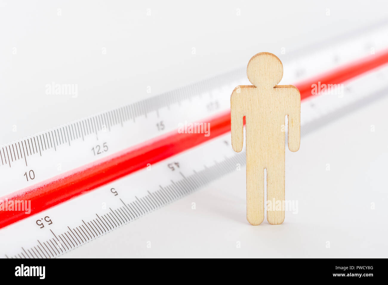 Makro kleine Laser-cut Holzfigur und Lineal. Metapher Messen persönliche Leistung, Demographie Konzept, Produktivität, die Maßnahme von einem Mann bekommen. Stockfoto