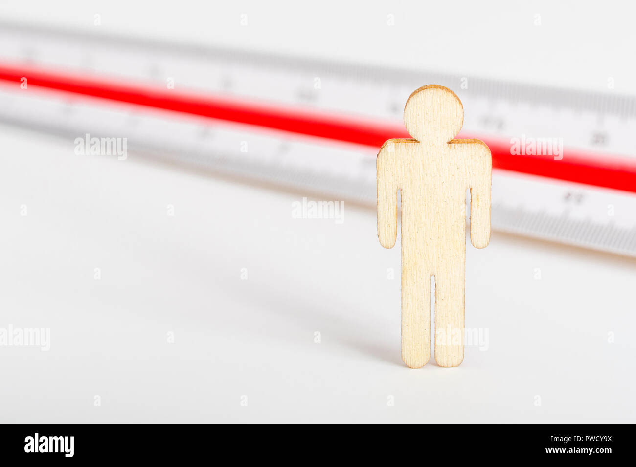Makro kleine Laser-cut Holzfigur und Lineal. Metapher Messen persönliche Leistung, Demographie Konzept, Produktivität, die Maßnahme von einem Mann bekommen. Stockfoto