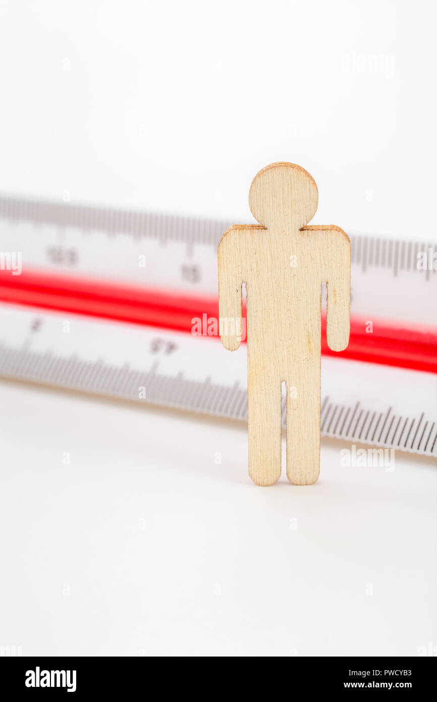 Makro kleine Laser-cut Holzfigur und Lineal. Metapher Messen persönliche Leistung, Demographie Konzept, Produktivität, die Maßnahme von einem Mann bekommen. Stockfoto