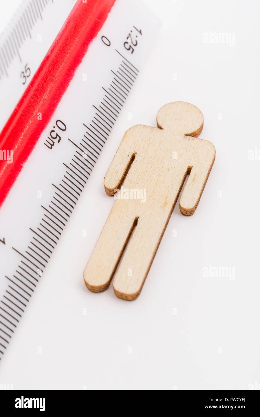 Makro kleine Laser-cut Holzfigur und Lineal. Metapher Messen persönliche Leistung, Demographie Konzept, Produktivität, die Maßnahme von einem Mann bekommen. Stockfoto