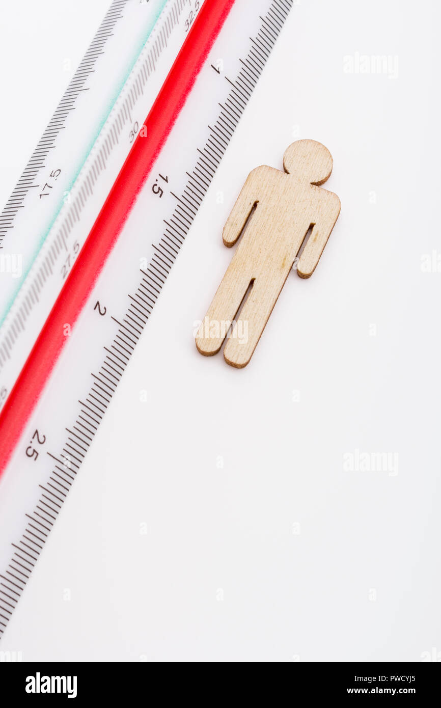 Makro kleine Laser-cut Holzfigur und Lineal. Metapher Messen persönliche Leistung, Demographie Konzept, Produktivität, die Maßnahme von einem Mann bekommen. Stockfoto