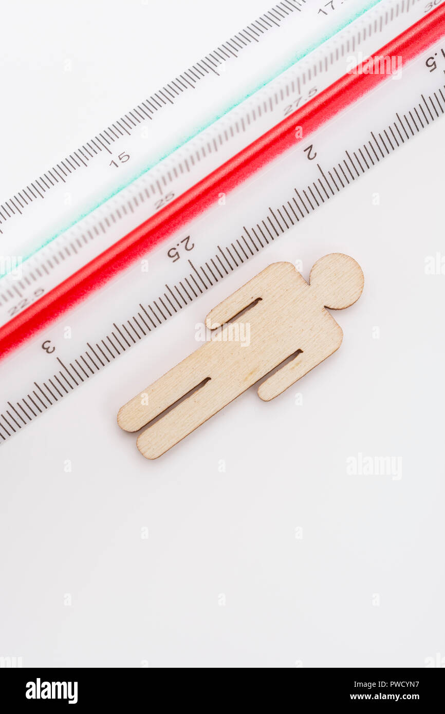 Makro kleine Laser-cut Holzfigur und Lineal. Metapher Messen persönliche Leistung, Demographie Konzept, Produktivität, die Maßnahme von einem Mann bekommen. Stockfoto