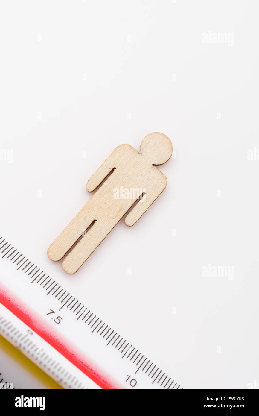 Makro kleine Laser-cut Holzfigur und Lineal. Metapher Messen persönliche Leistung, Demographie Konzept, Produktivität, die Maßnahme von einem Mann bekommen. Stockfoto