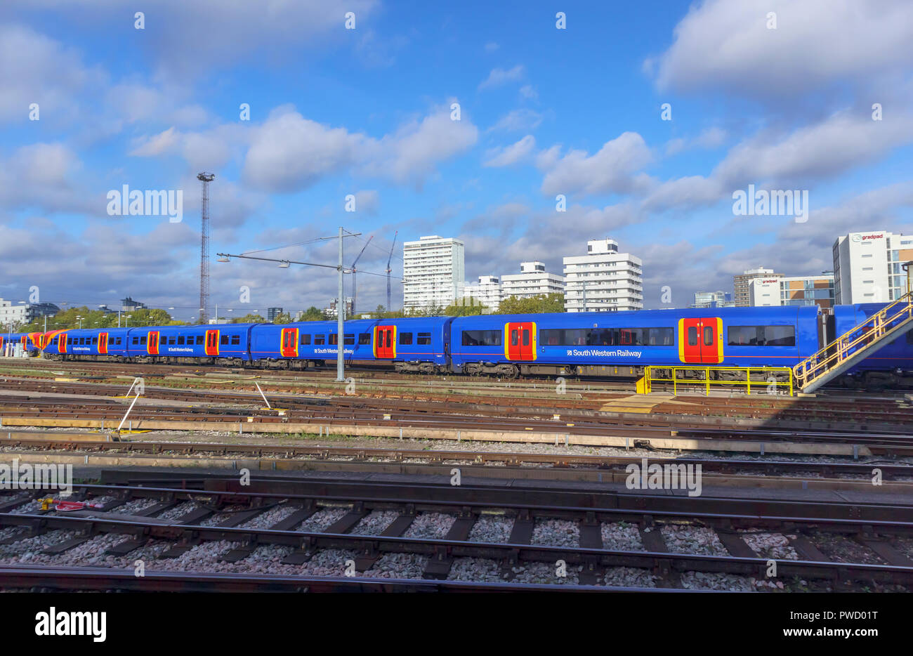 Bunte blau South Western Railway suburban Nahverkehrszug und Kutschen in Rangierbahnhofs in Clapham Junction Station, London, UK an einem sonnigen Tag Stockfoto