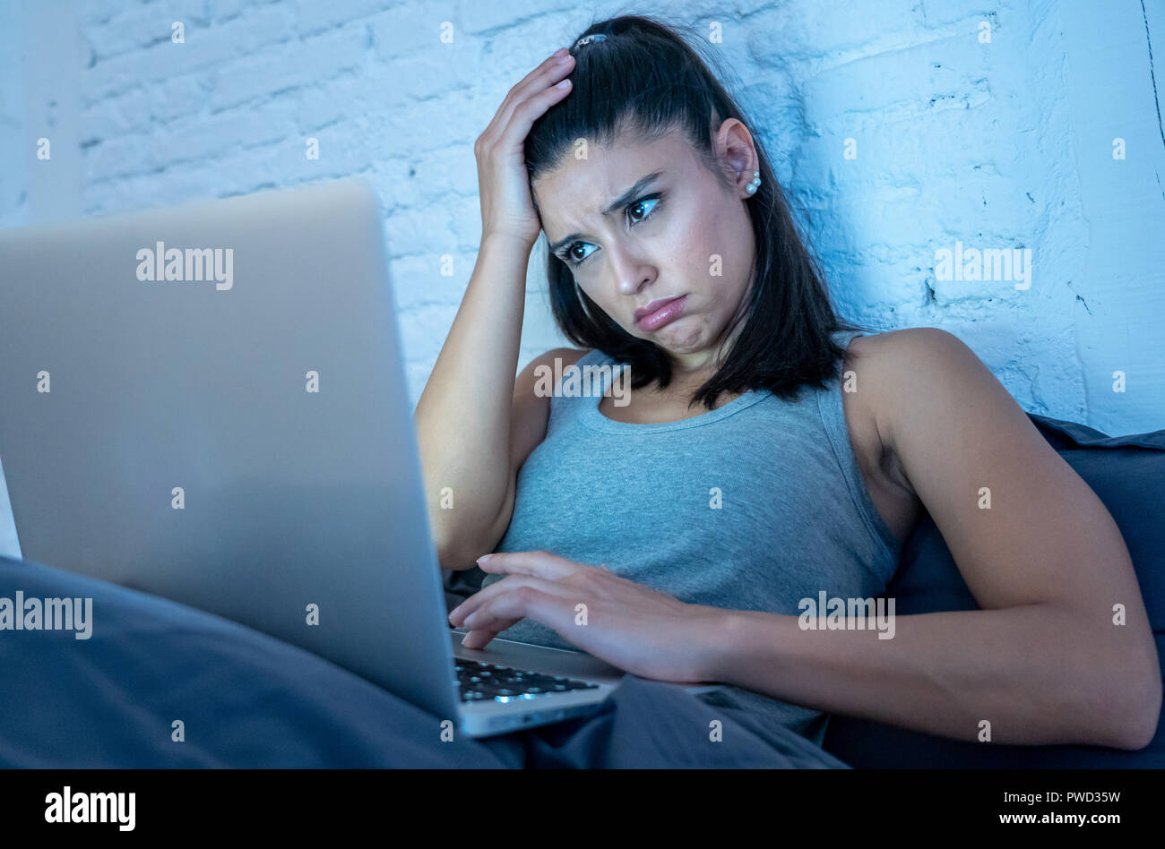 Attraktive junge Frau Arbeiten und Surfen im Internet mit Computer auf dem Sofa zu Hause spät in der Nacht im Internet sucht und Überarbeitung co Müde Stockfoto