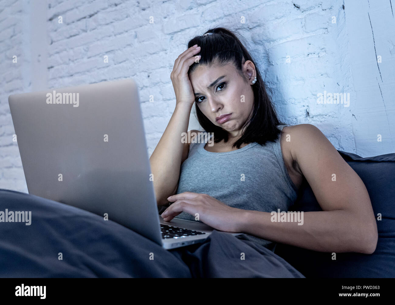 Attraktive junge Frau Arbeiten und Surfen im Internet mit Computer auf dem Sofa zu Hause spät in der Nacht im Internet sucht und Überarbeitung co Müde Stockfoto
