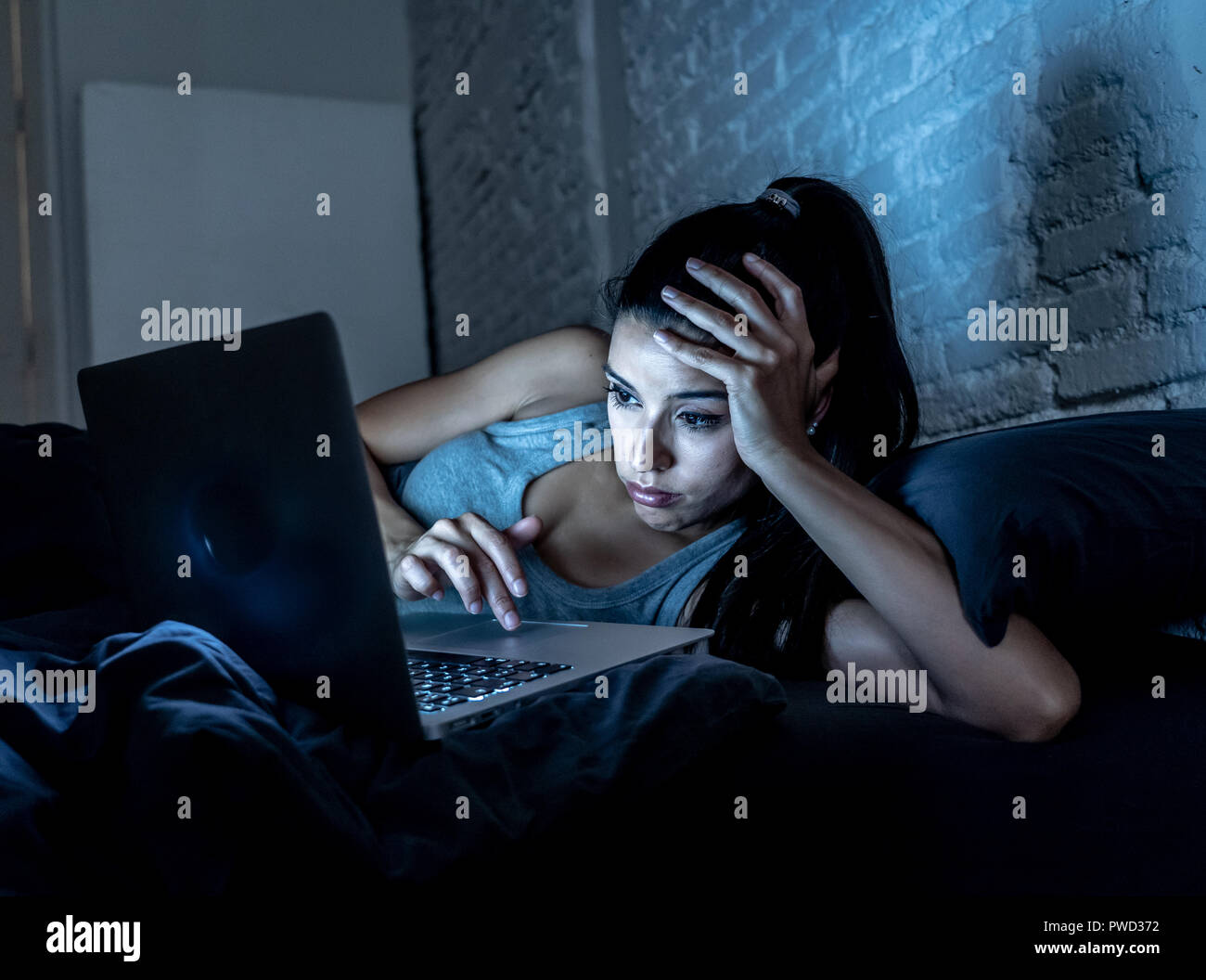 Attraktive junge Frau Arbeiten und Surfen im Internet mit Computer auf dem Sofa zu Hause spät in der Nacht im Internet sucht und Überarbeitung co Müde Stockfoto