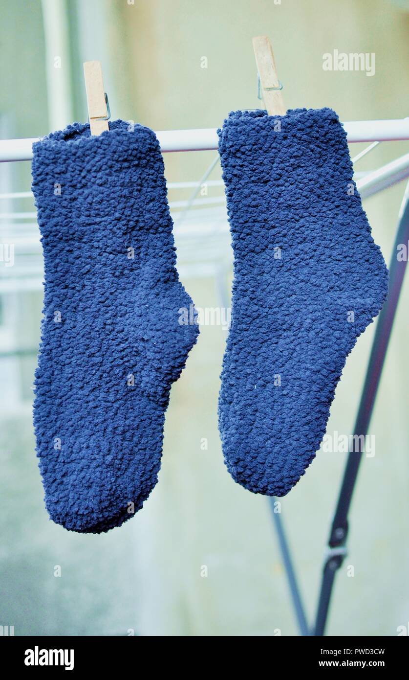 Ein paar blaue Socken mit Holz zu trocknen Haken am Rack Stockfoto