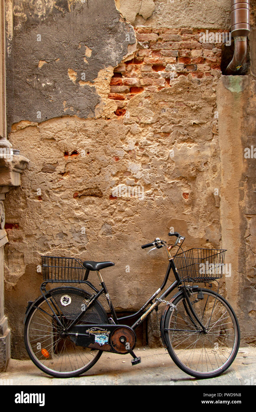 Ein Fahrrad lehnt sich gegen eine alte und verwitterte Wand in einer Gasse in Florenz, Italien. Stockfoto