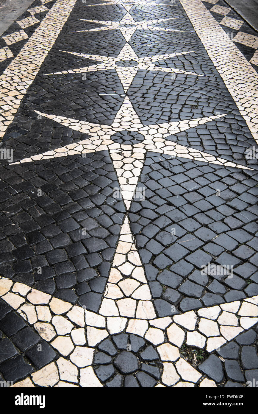 Klassische schwarze und weiße glänzende Kopfsteinpflaster im symmetrischen Stern und Raute Formen in Street im Zentrum von Lissabon in Portugal Stockfoto