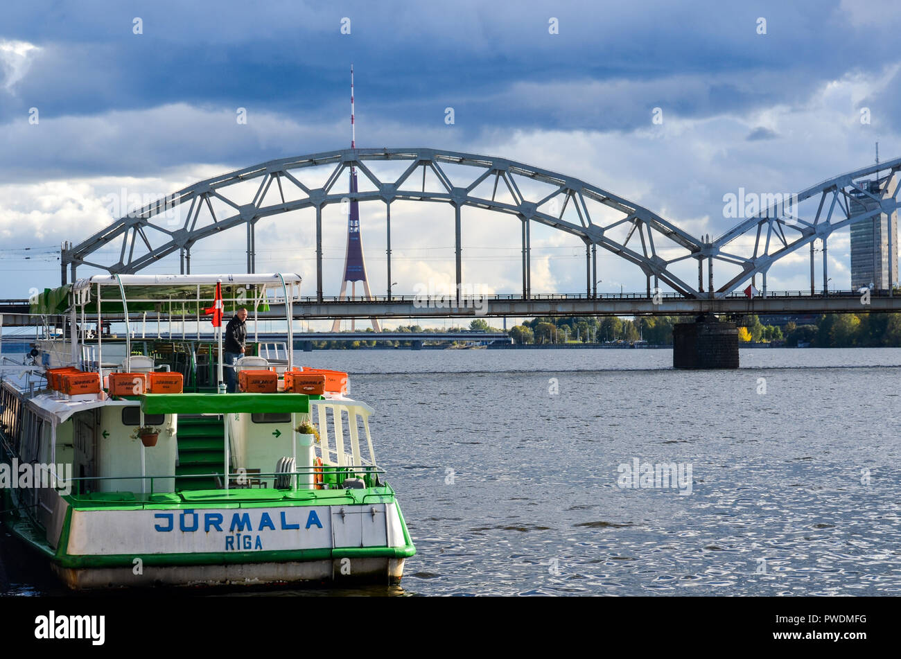 Lettische Eisenbahn Zug vorbei über die Eisenbahnbrücke, Riga, Lettland, über den Fluss Daugava, mit der Radio- und TV-Turm im Hintergrund Stockfoto